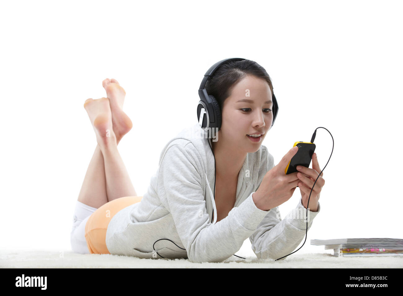 young woman lying on her front listening to music. Stock Photo