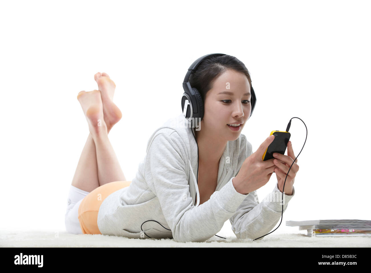 young woman lying on her front listening to music Stock Photo - Alamy