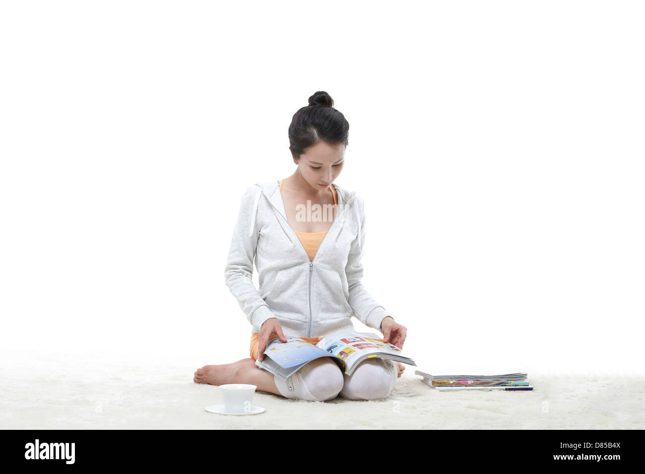 young woman sitting reading magazine. Stock Photo