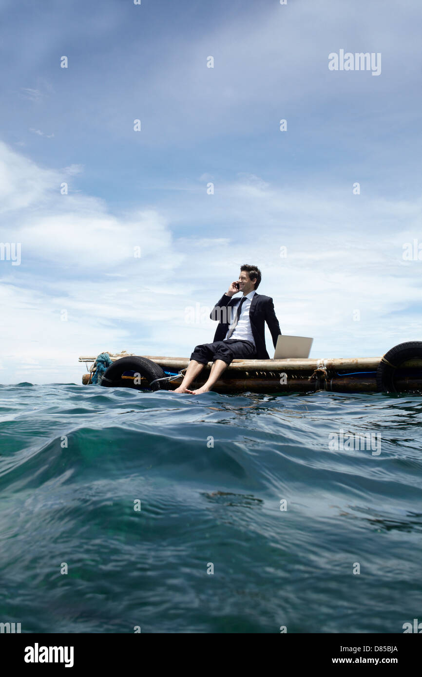 businessman sitting on dock laptop mobile phone. Stock Photo