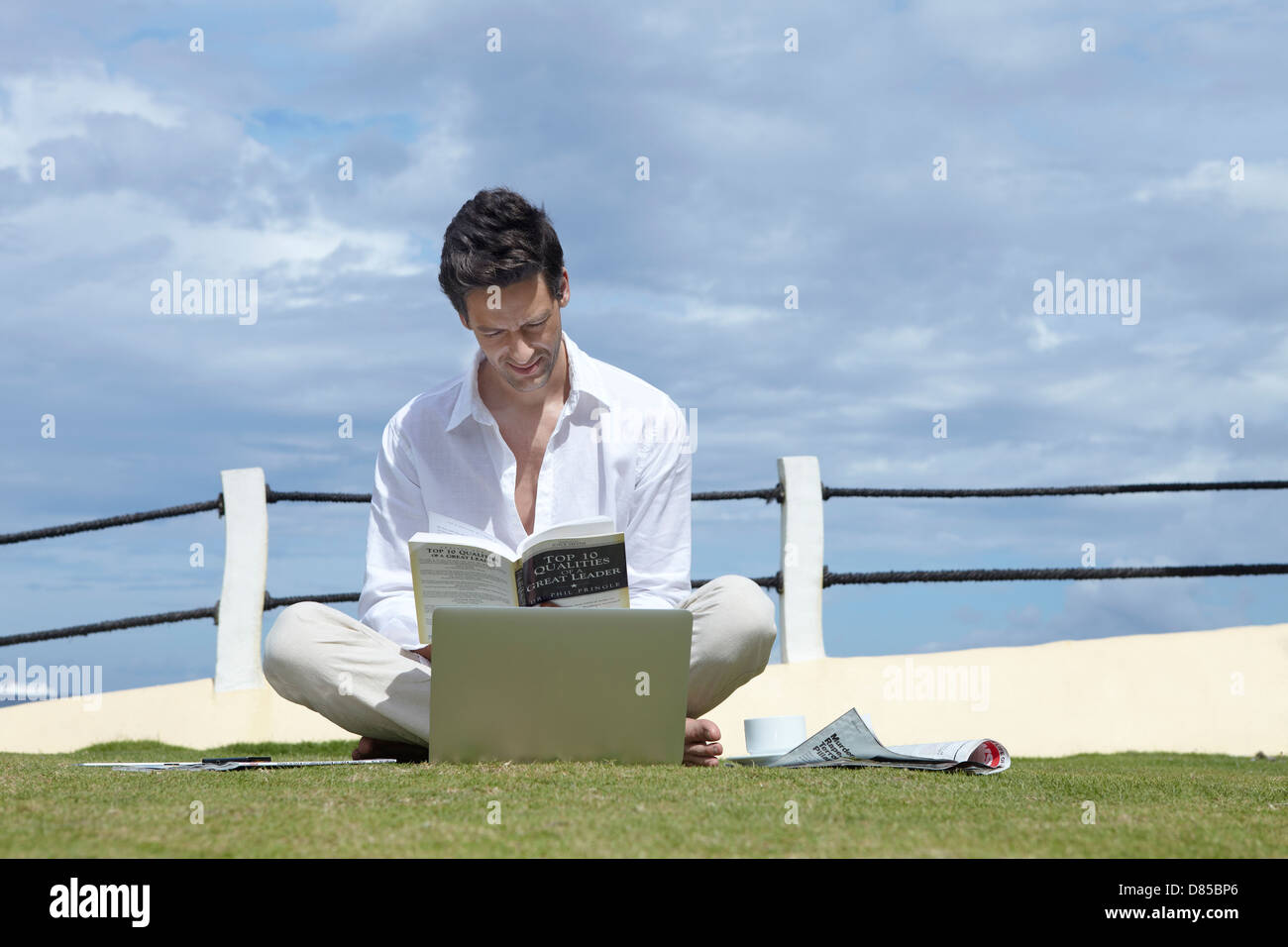 man sitting cross-legged on grass working on laptop Stock Photo - Alamy