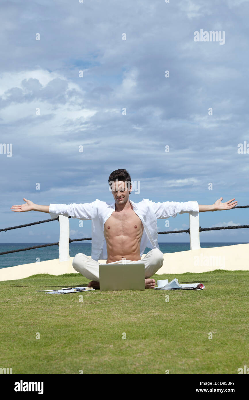 man sitting cross-legged on grass working on laptop Stock Photo - Alamy