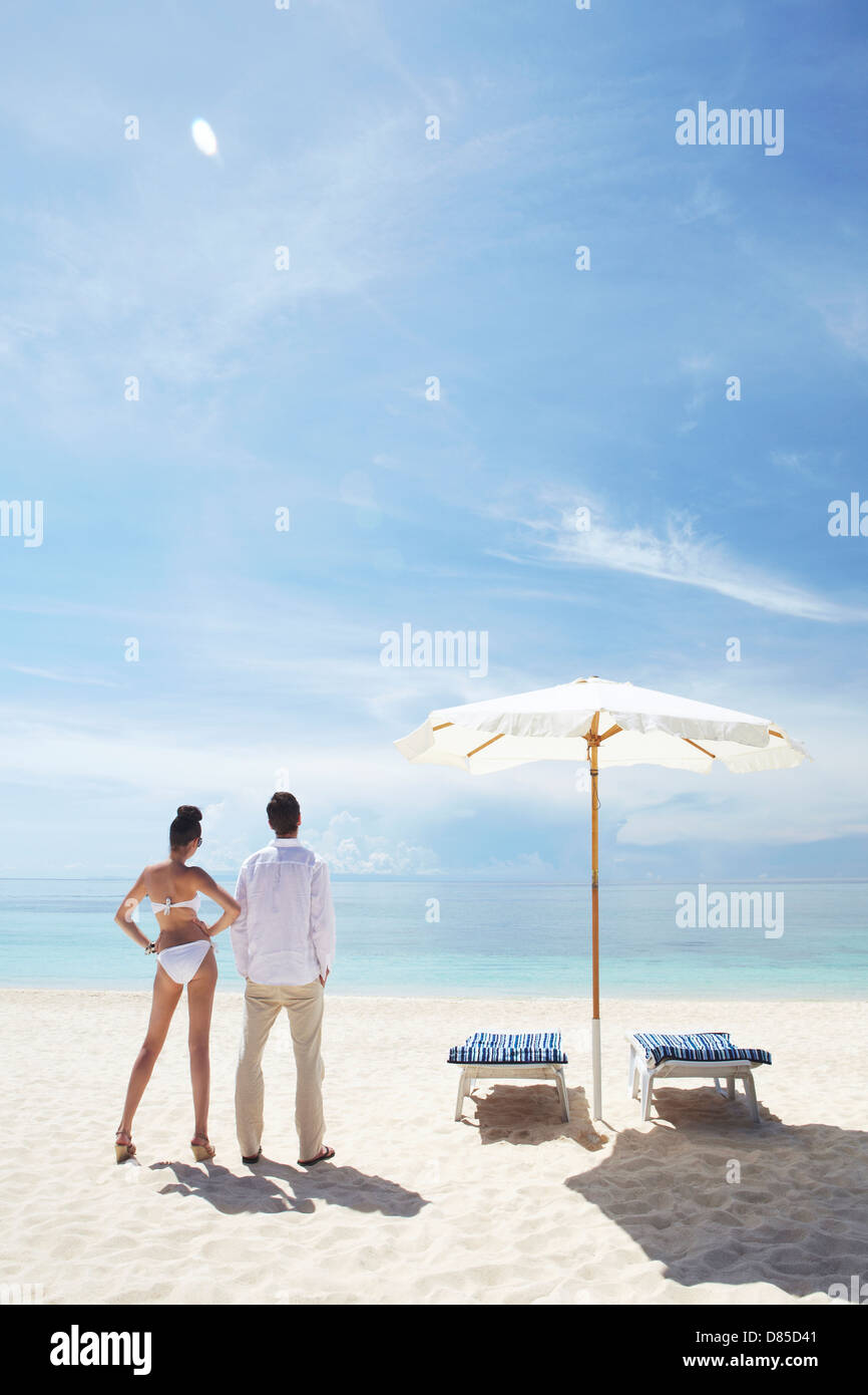 couple standing on beach their backs to camera. Stock Photo