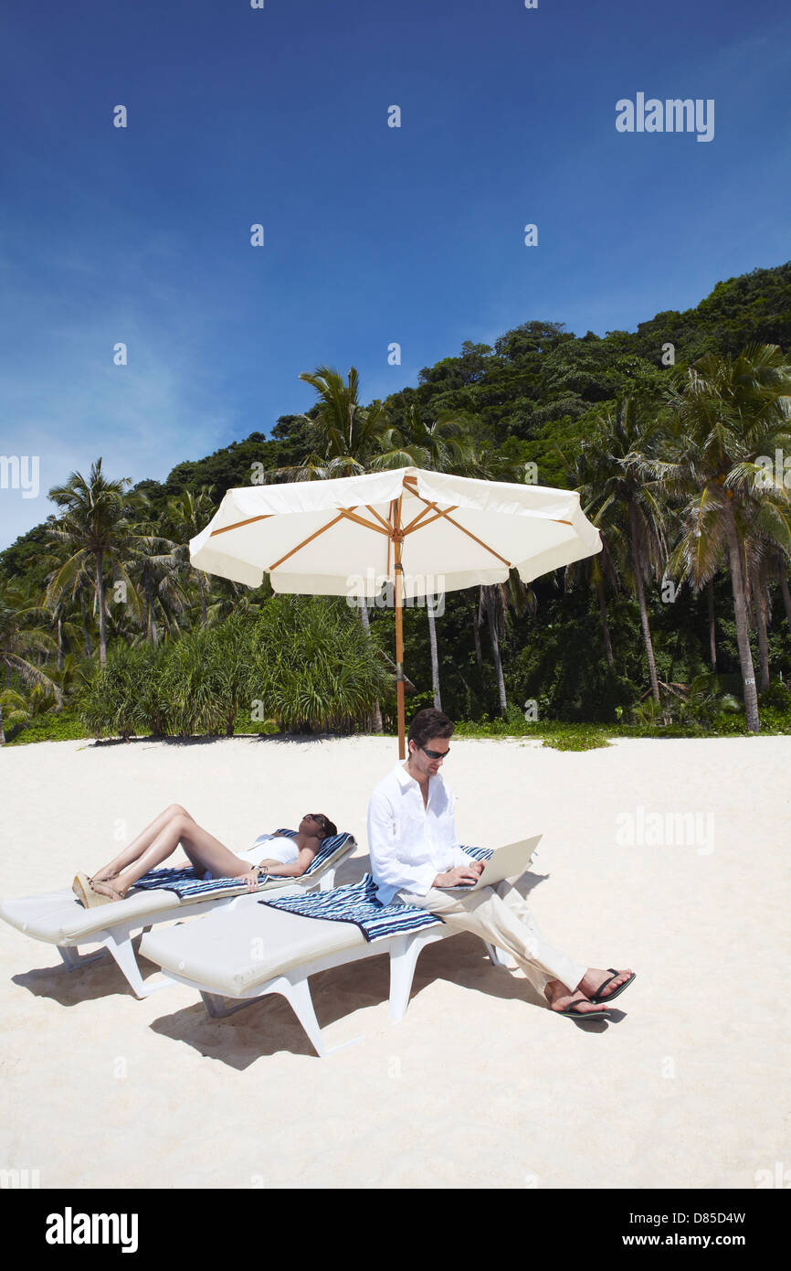 couple relaxing in deck chairs on beach Stock Photo - Alamy