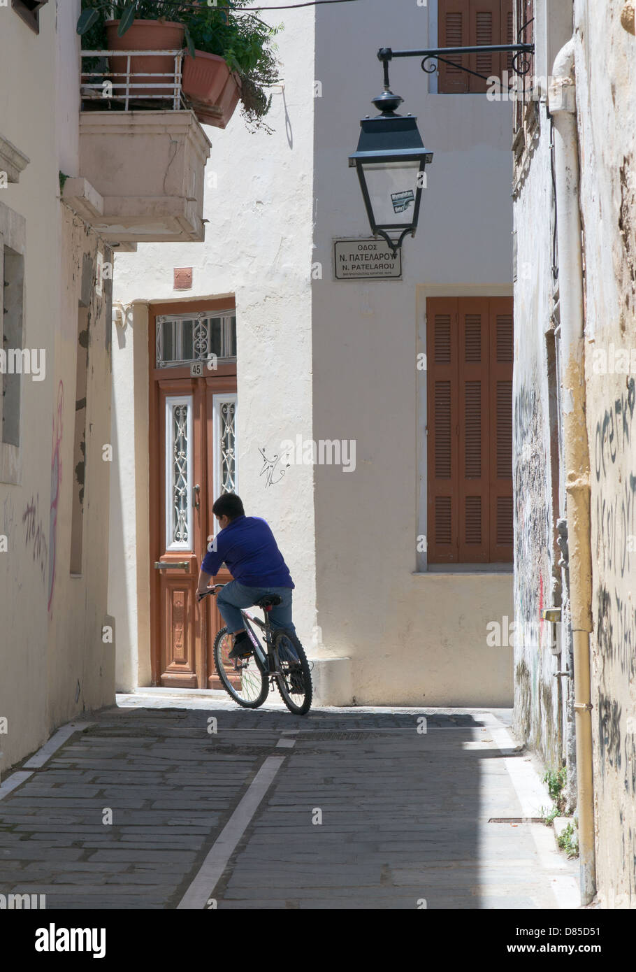 A solitary cyclist rounds a bend within an alley in the old town of Rethymno, Crete Stock Photo