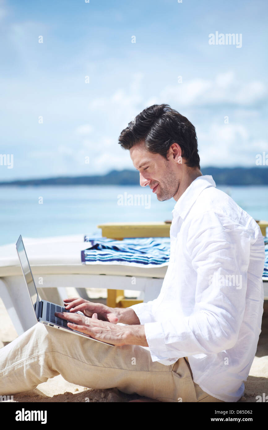 man sitting cross-legged on beach laptop Stock Photo - Alamy