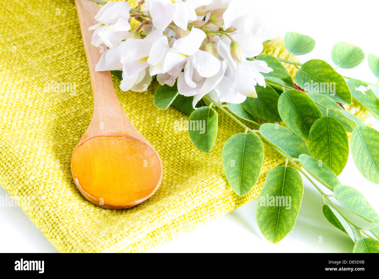 Acacia honey in spoon with flower and leaves Stock Photo