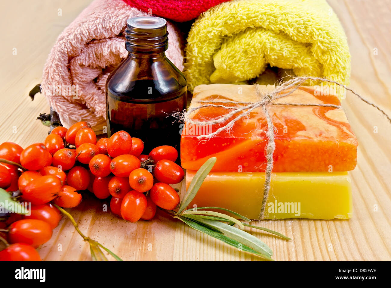 Oil in a bottle, two homemade soap, towels, twig and berries of sea