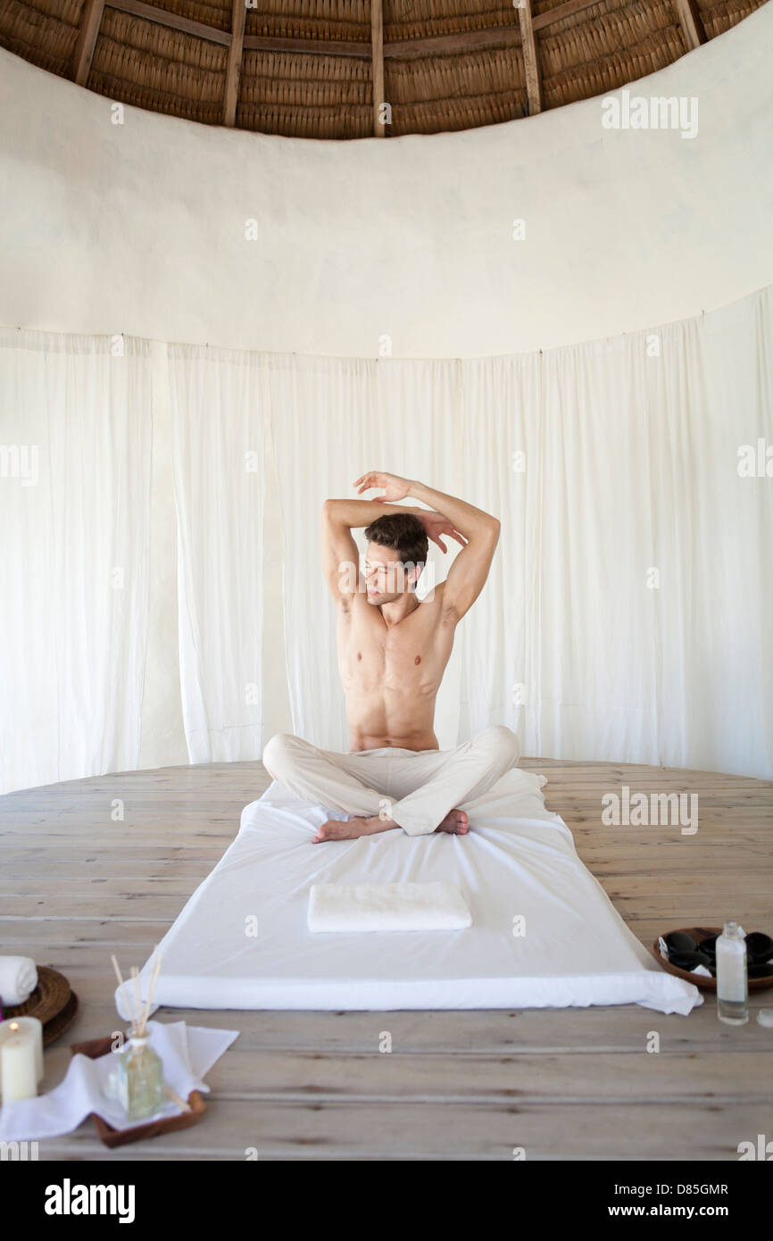 man sitting cross-legged stretching. Stock Photo