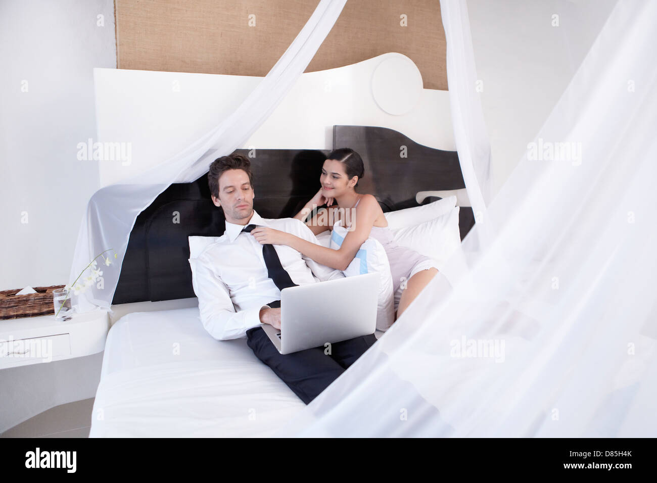young couple sitting on bed laptop. Stock Photo