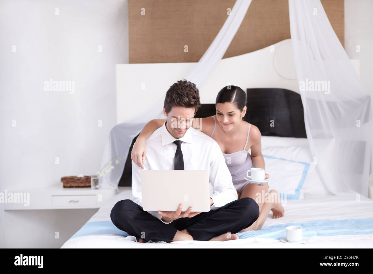 young couple sitting on bed laptop. Stock Photo