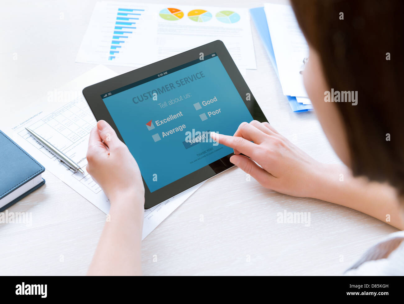 Businesswoman holding modern digital tablet with customer service survey form on a screen. Red tick on excellent choice option Stock Photo