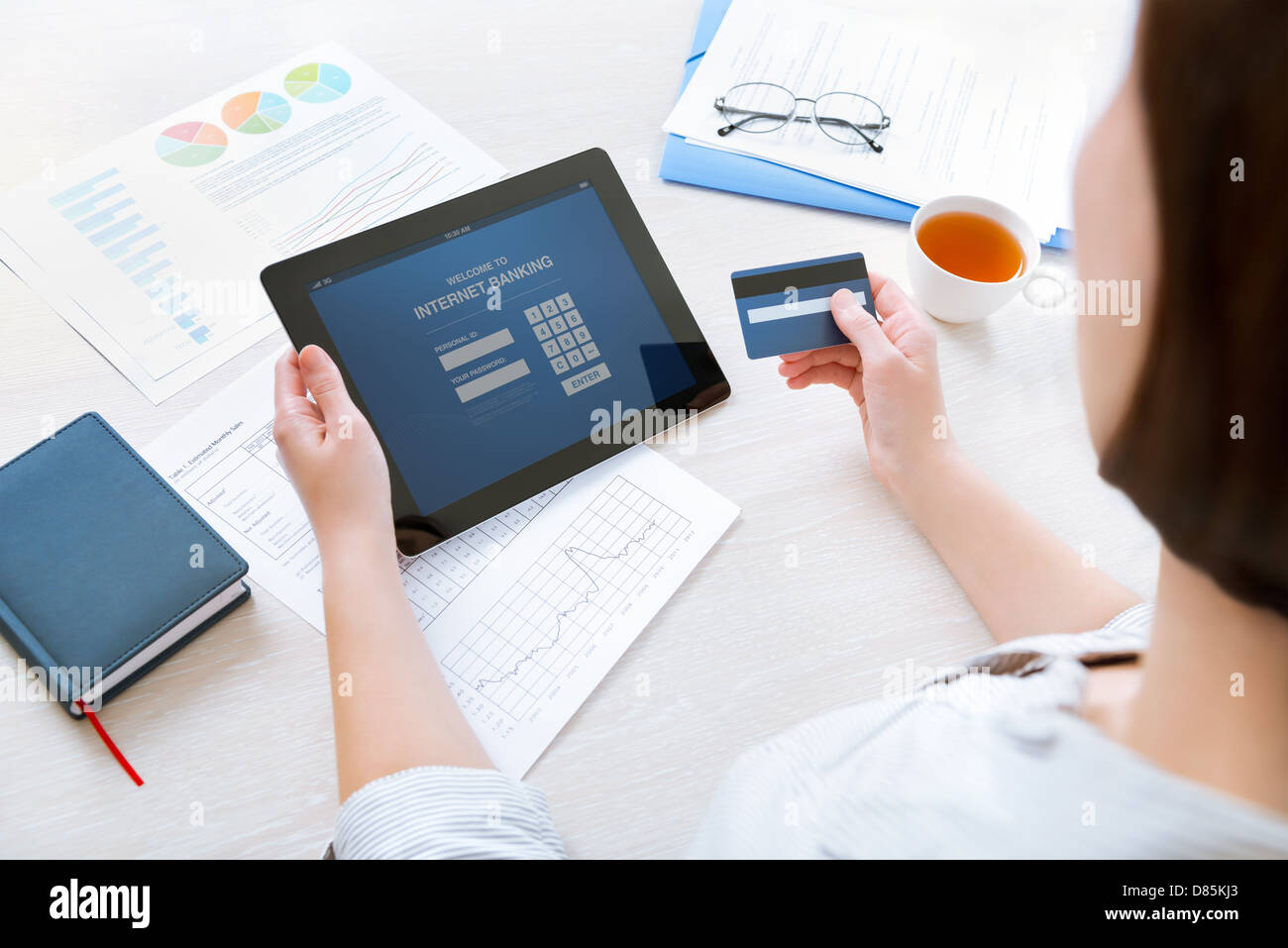 Successful businesswoman inputting login information to carry out online banking operation on digital tablet in the office Stock Photo