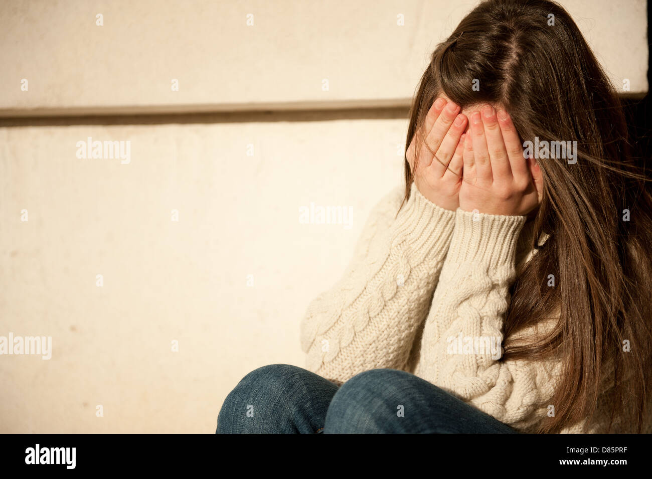 Teenage girl with both hands covering her face. Stock Photo