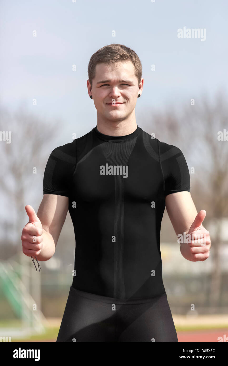 Young athlete stands in a stadium and shows thumbs up Stock Photo
