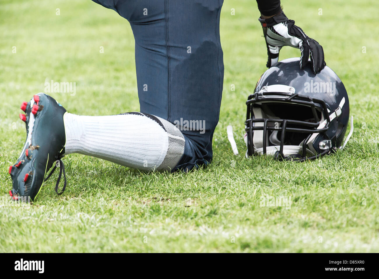 American football player kneels on the playground Stock Photo