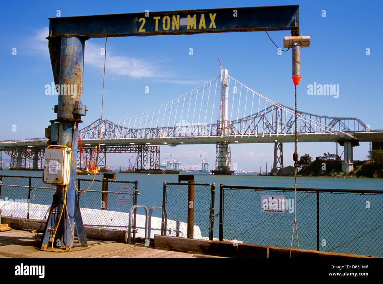 view of new bay bridge construction from treasure island dock with 2 ton boat dock crane in foreground Stock Photo
