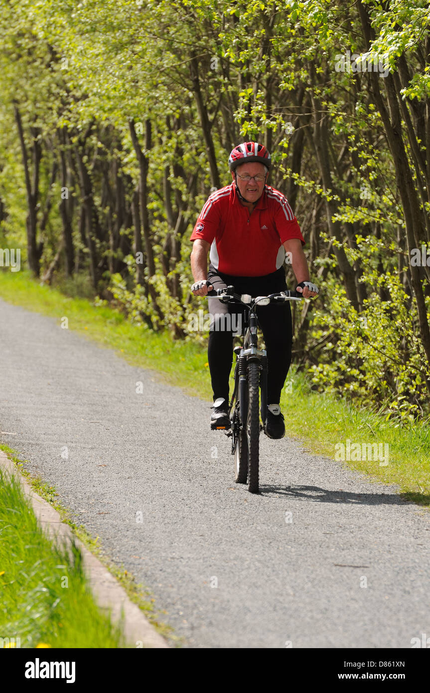 Mature gentleman cycling on the foot and cycle path adjacent to the Forth and Clyde canal in Glasgow, Scotland, UK Stock Photo