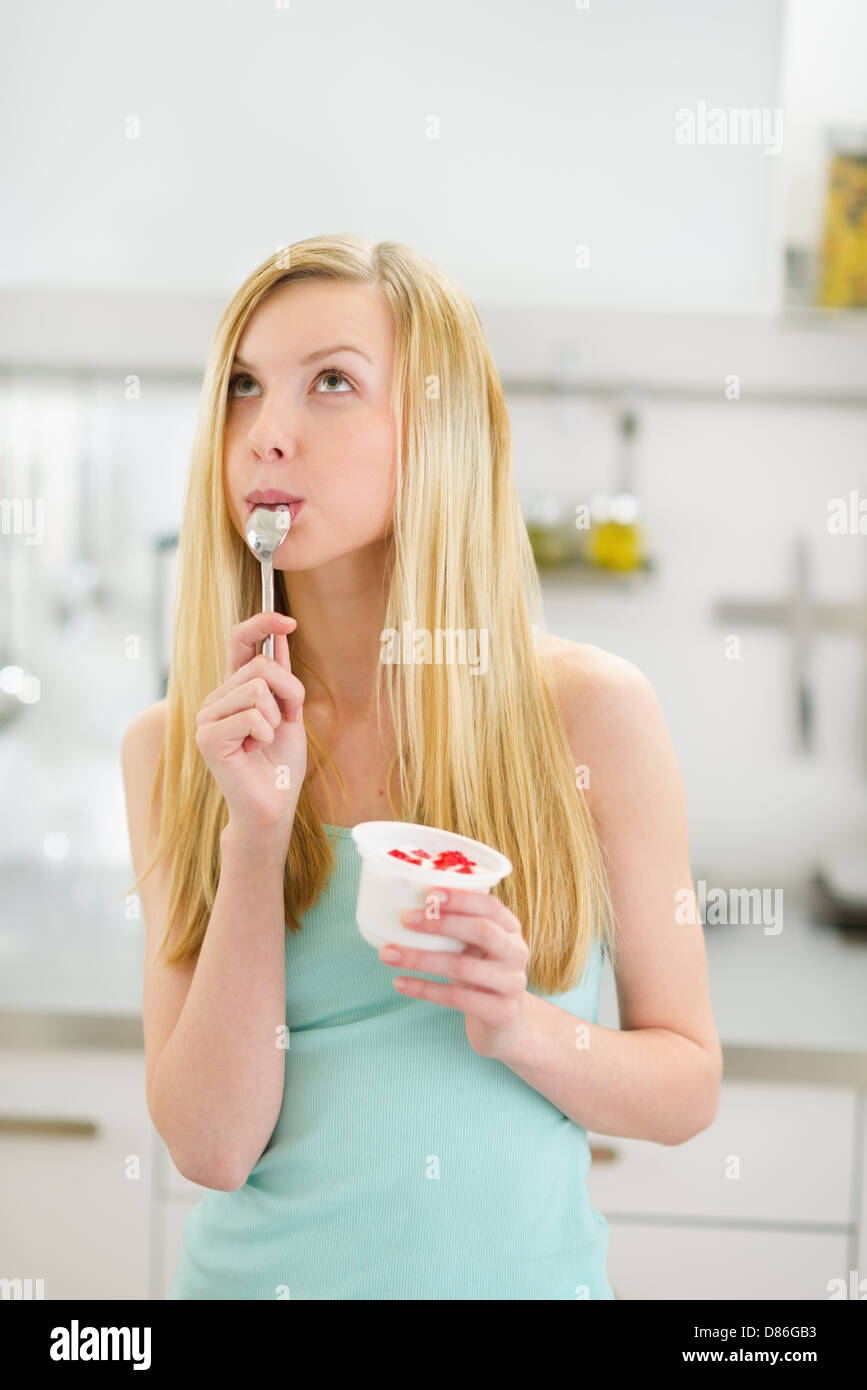 Thoughtful teenager girl eating yogurt in kitchen Stock Photo Alamy
