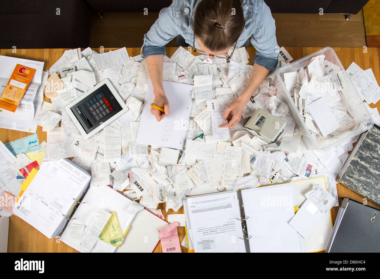 Young woman is sitting at home and sort out bills, receipts and other ...