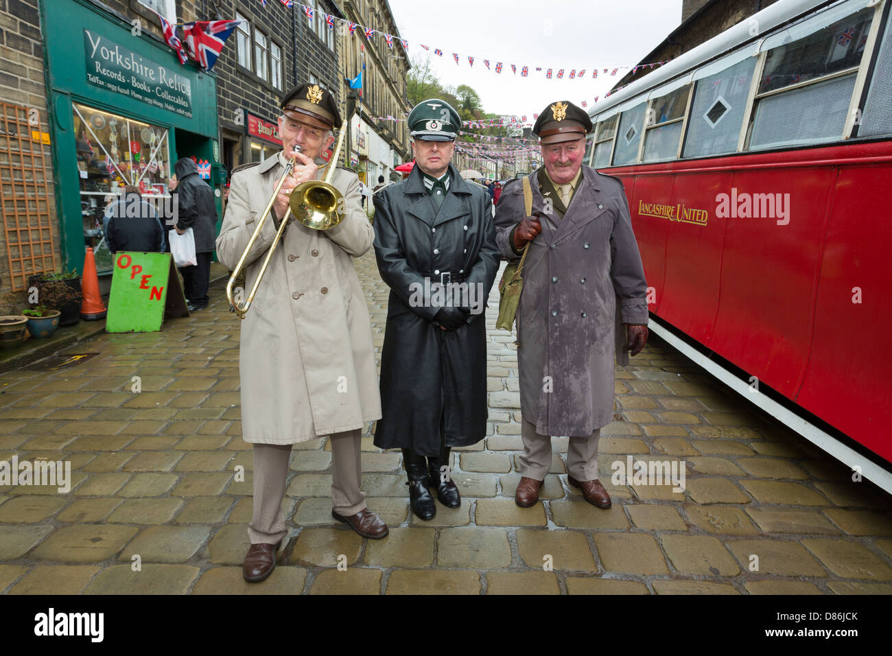 Two men in American Army uniforms, one playing a trombone, with a man in Germany Army uniform. Haworth 1940s weekend, May 2013. Stock Photo