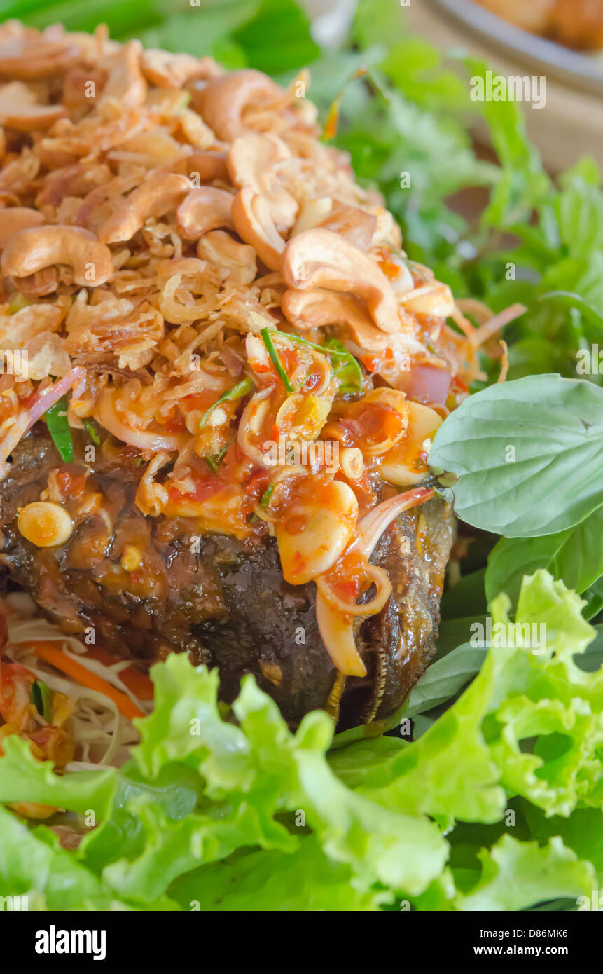 fried fish served with fresh vegetable and spicy sauce , fried garlic