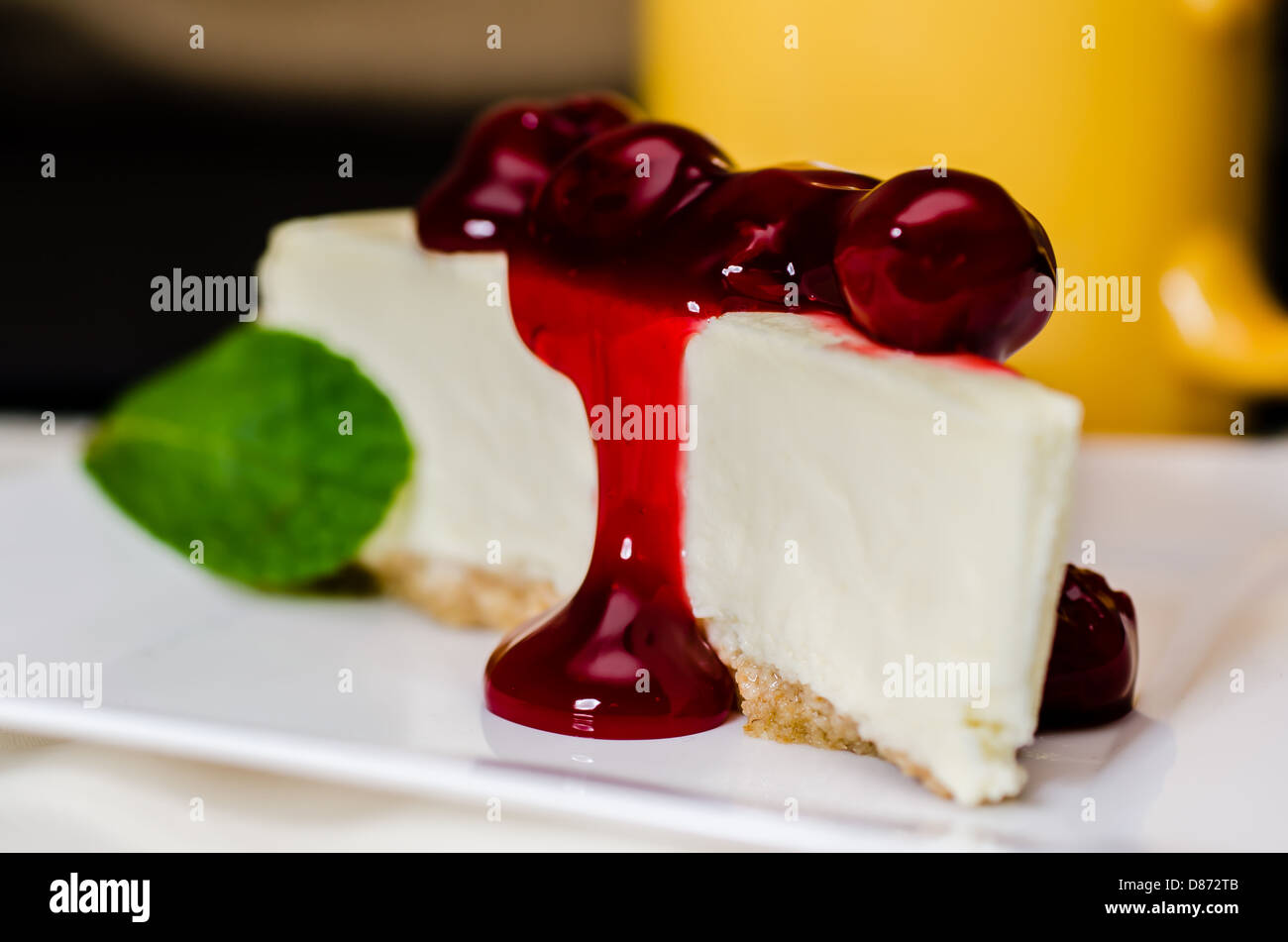 Slice of cherry cheesecake and coffee with mint garnish. Shallow depth of field. Stock Photo