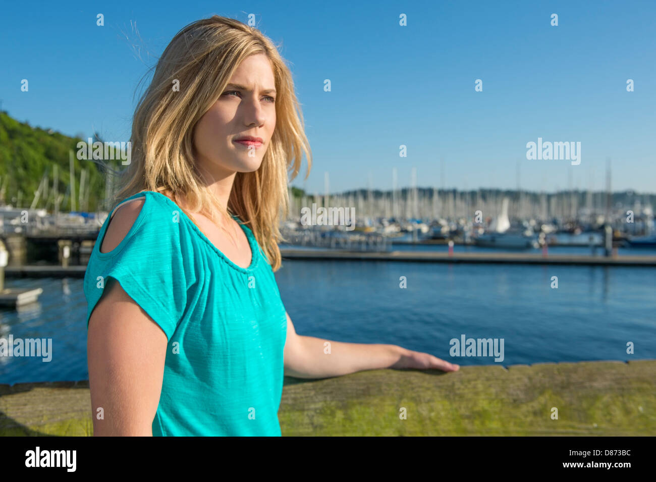 Beautiful young woman looking away while standing at harbor Stock Photo
