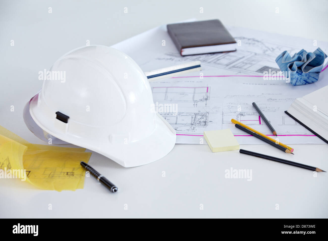 Blueprints, helmet and pens on the desk of an architect Stock Photo