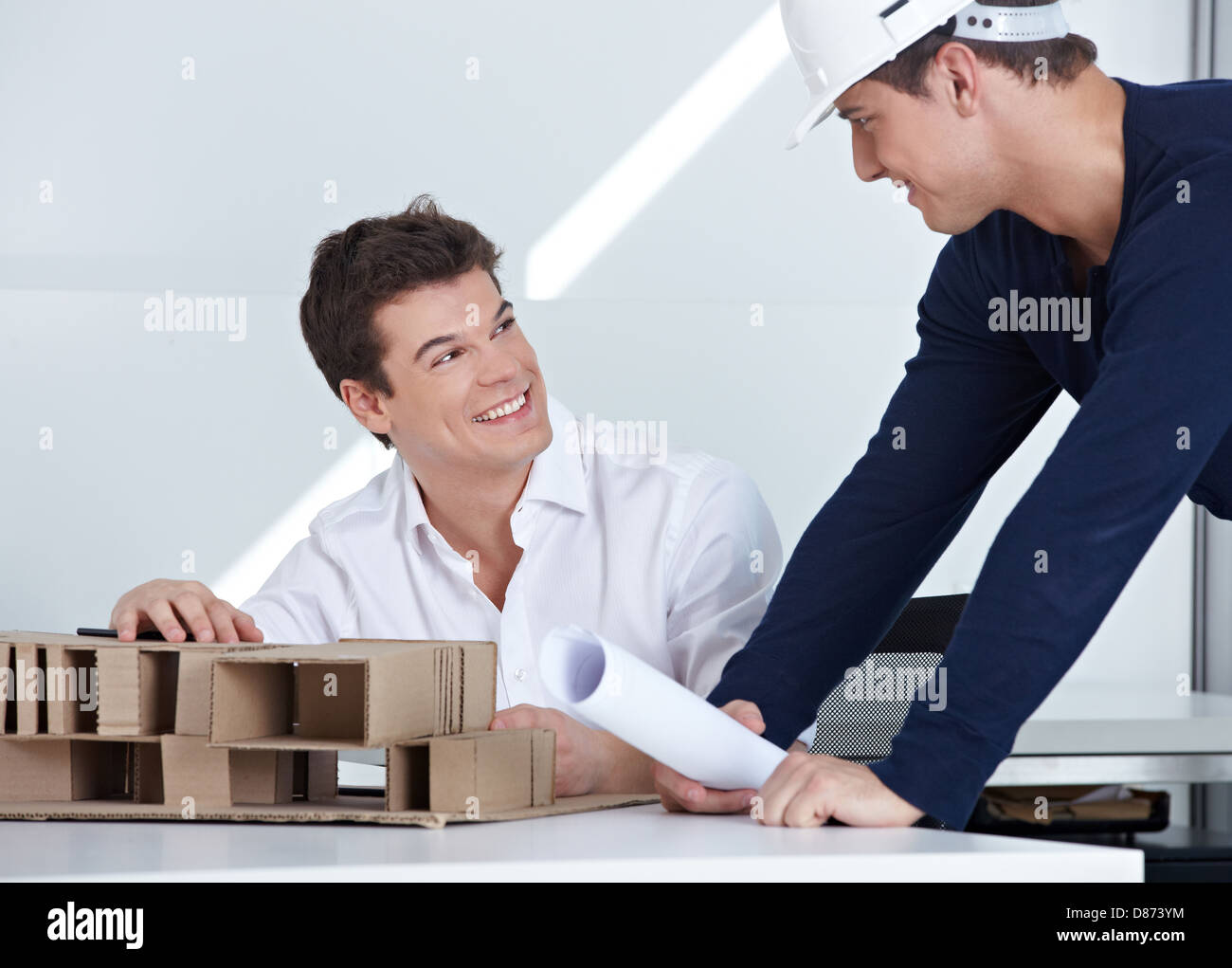 Architect with hardhat and blueprint talking to his employees in the office Stock Photo