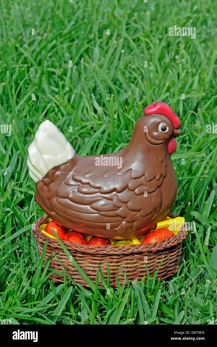 Chocolate Easter chicken with eggs in a basket on grass. Stock Photo