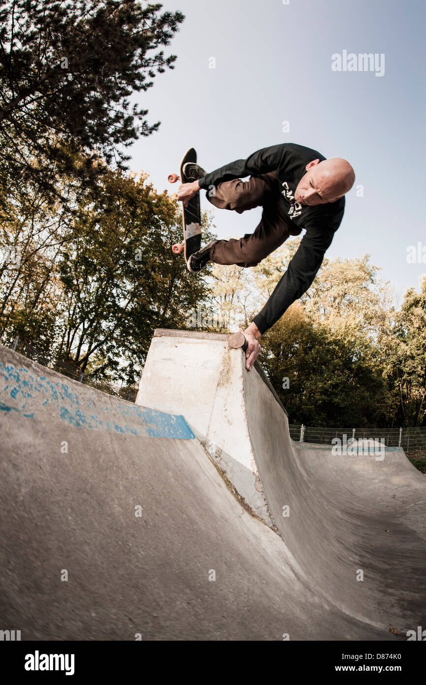 Germany, North Rhine Westphalia, Duesseldorf, Mature man jumping with skateboard Stock Photo
