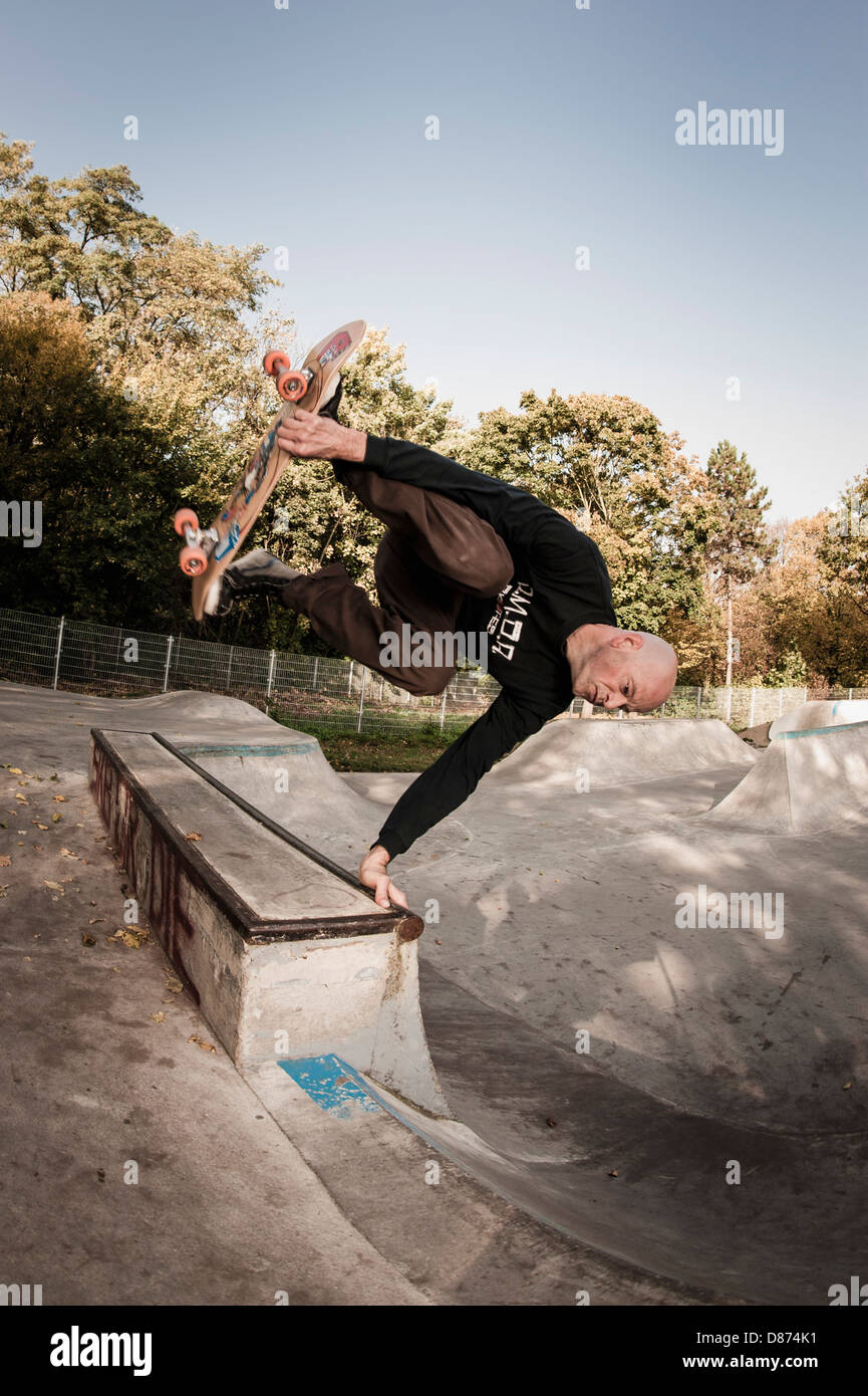 Germany, North Rhine Westphalia, Duesseldorf, Mature man jumping with skateboard Stock Photo