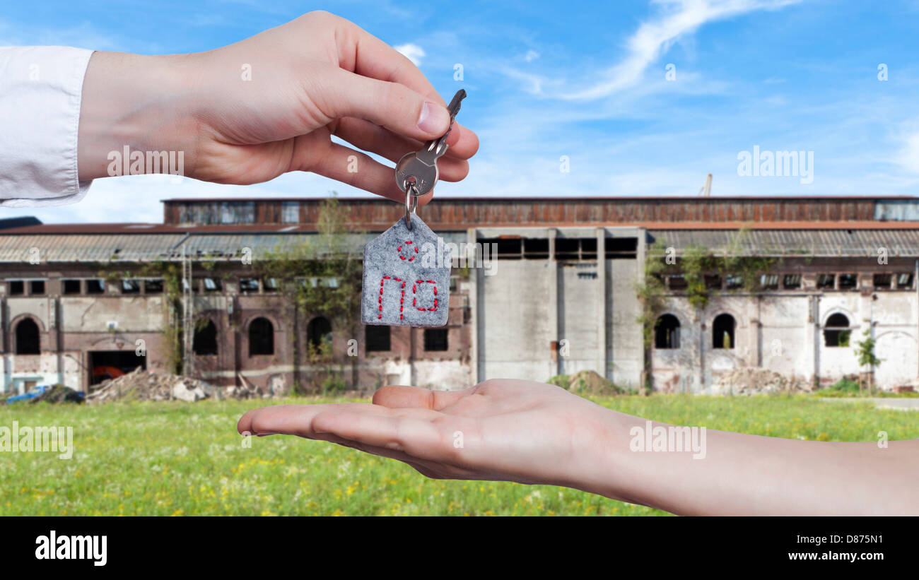 Germany, Human hands exchanging house key in front of very old and broken down factory building Stock Photo