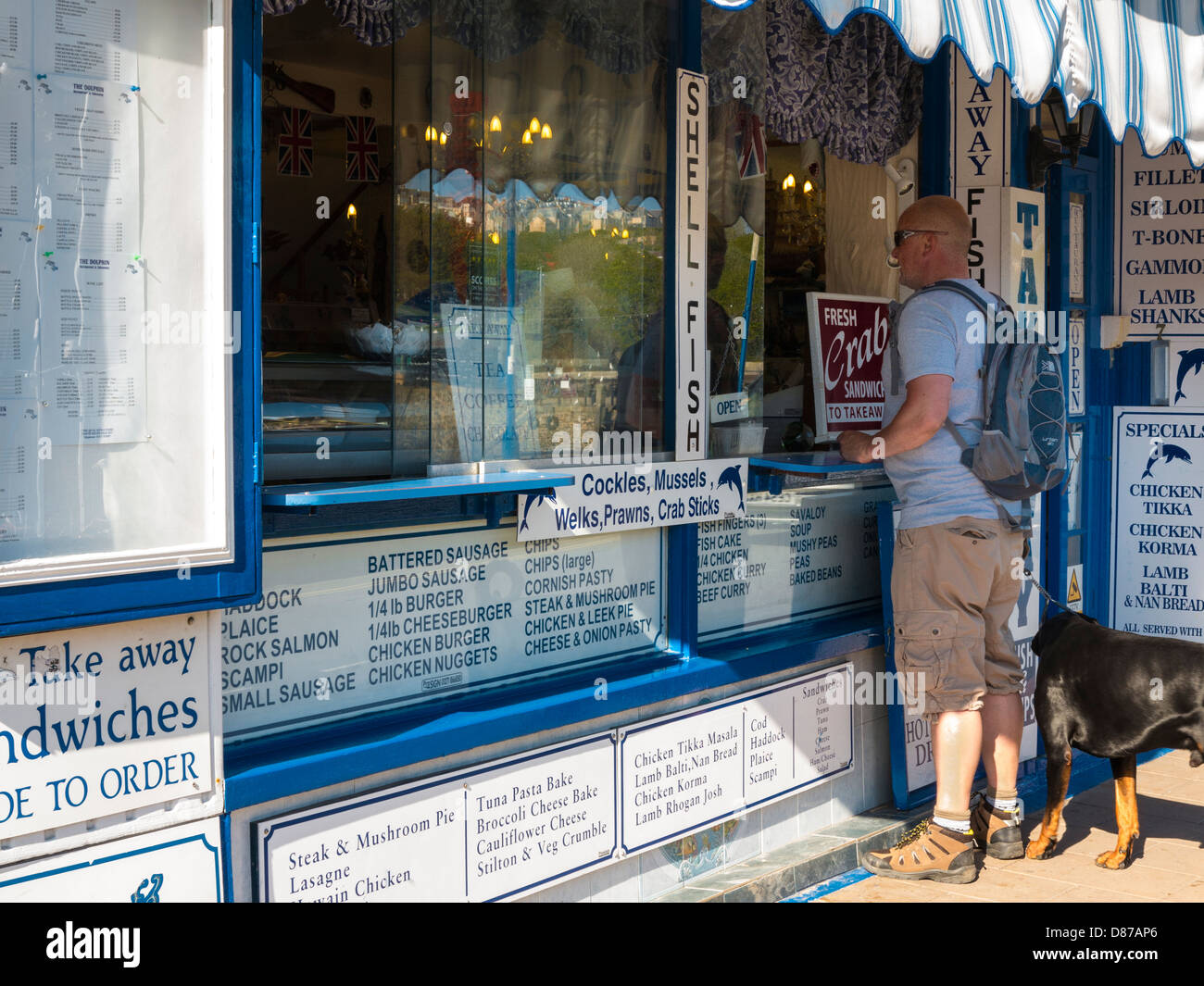 Seafood takeaway restaurant with man and dog at Ilfracombe, Devon, England Stock Photo