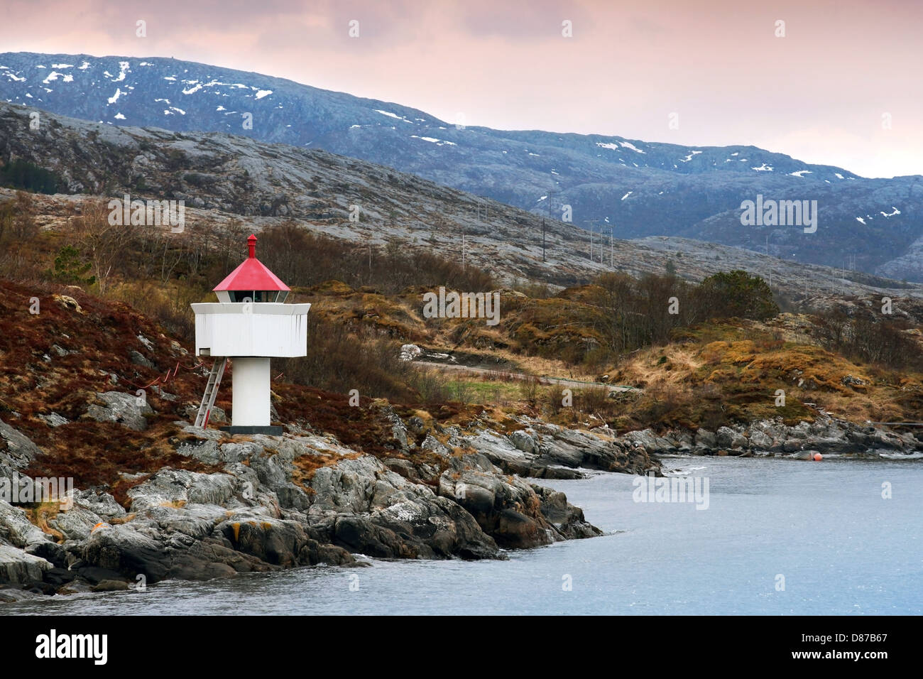 Norwegian lighthouse. White tower with red top stands on coastal rocks ...