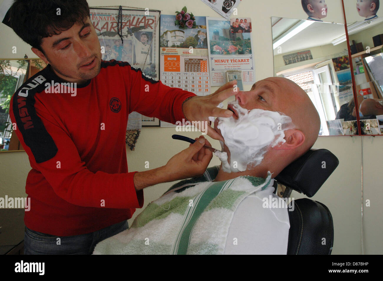 Barber shaving and grooming men in Turkish village barber shop Stock