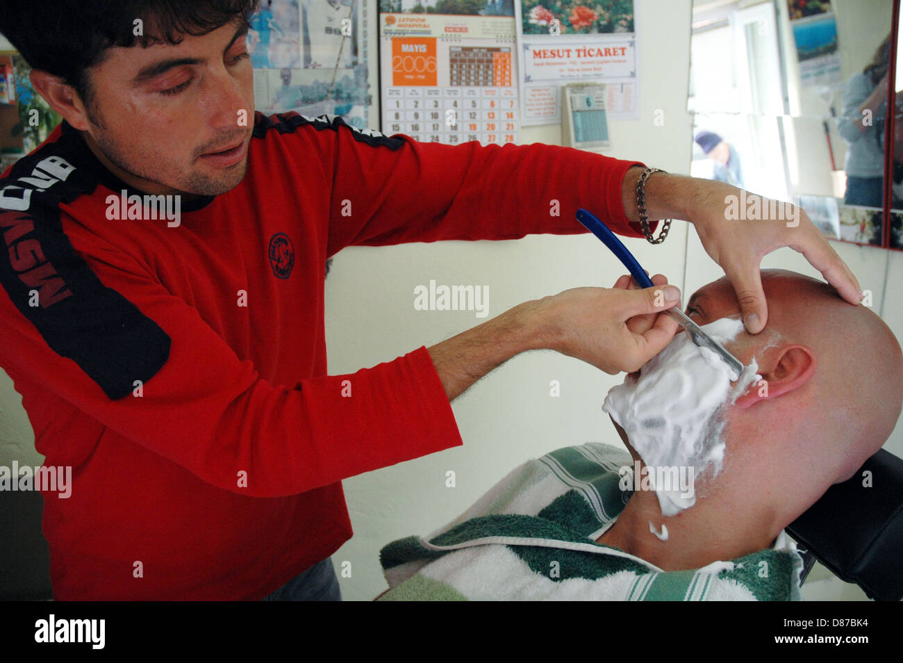 Barber shaving and grooming men in Turkish village barber shop Stock