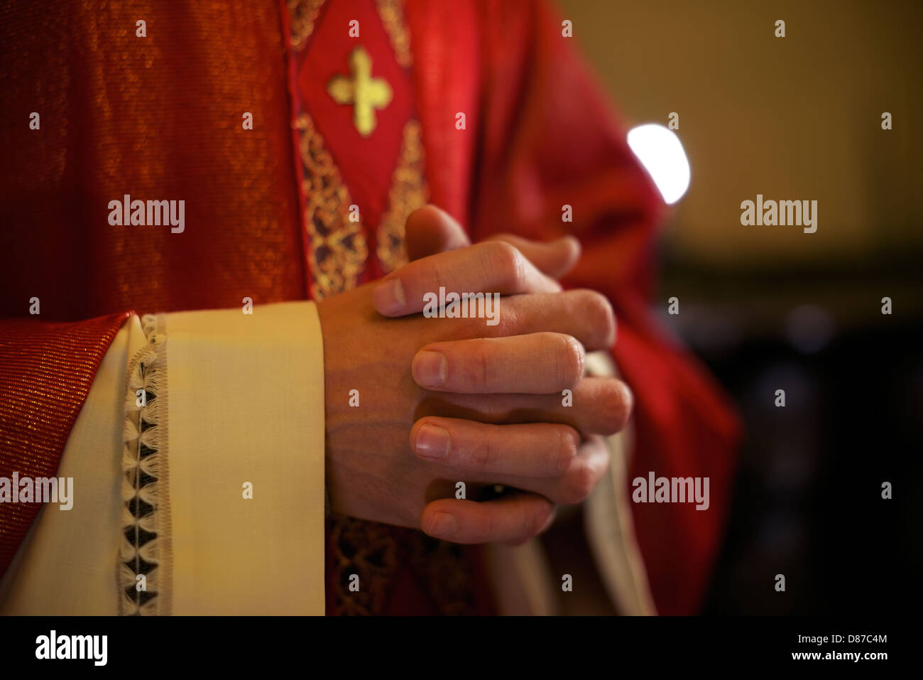 Catholic priest on altar praying with hands joined during mass service in church Stock Photo