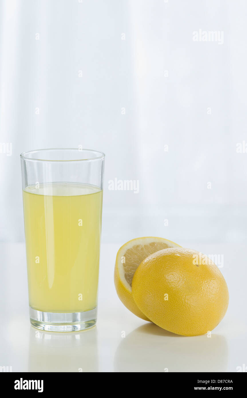 Glass of grapefruit juice beside grapefruit against white background