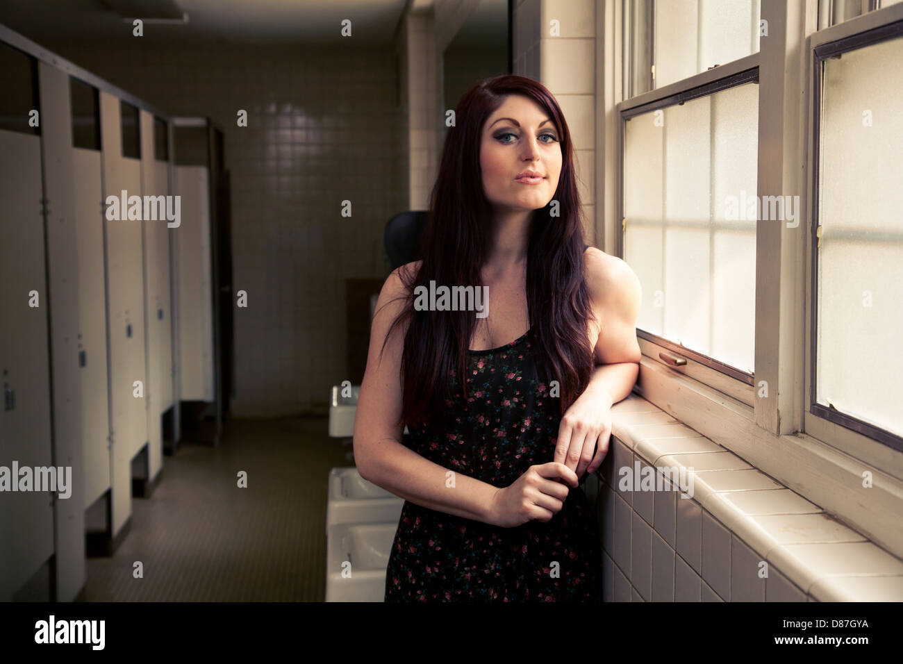 Woman standing next to window in public bathroom Stock Photo