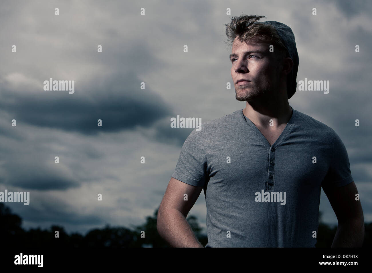 Man staring off into the light against cloudy sky Stock Photo