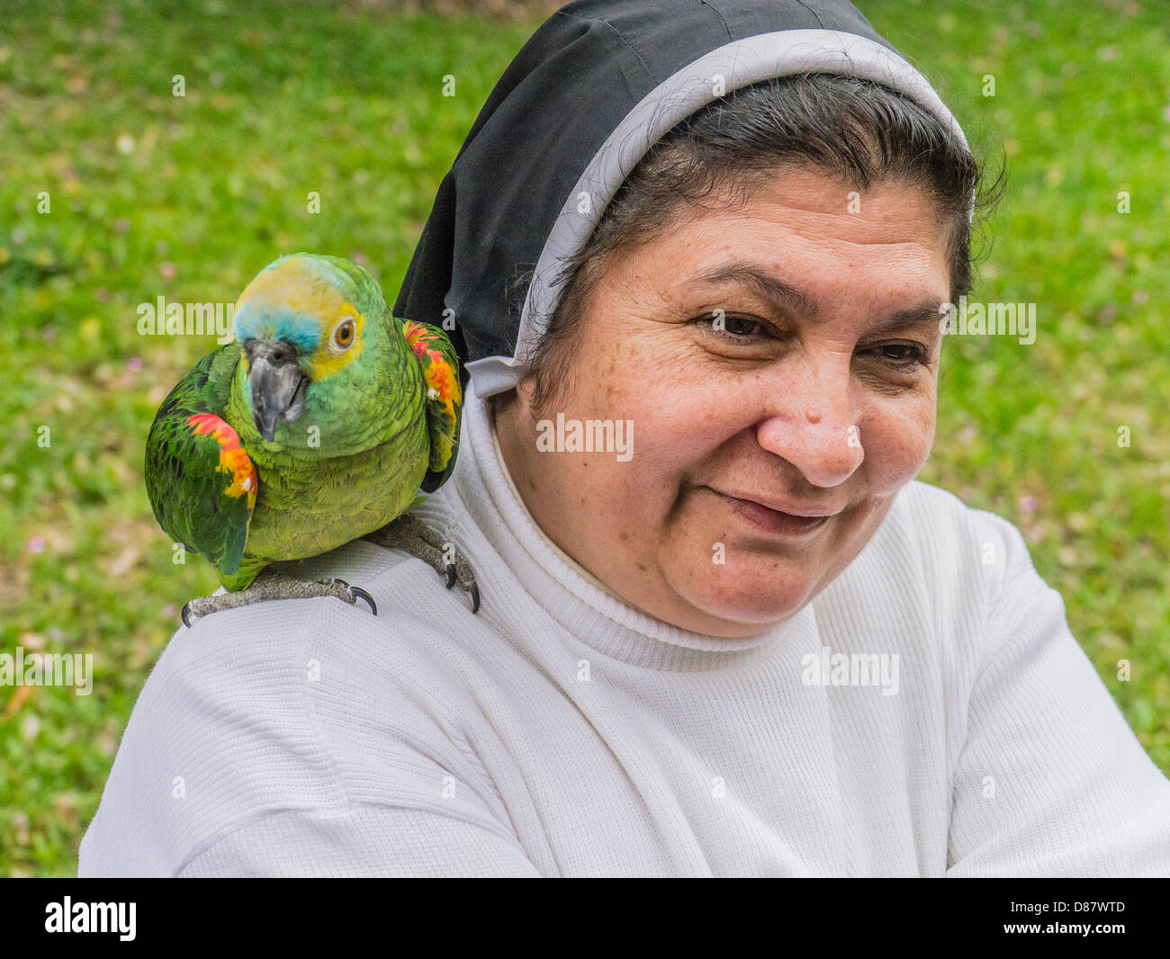 A Paraguayan nun has a pet parrot on her shoulder in a close-up portrait. Stock Photo
