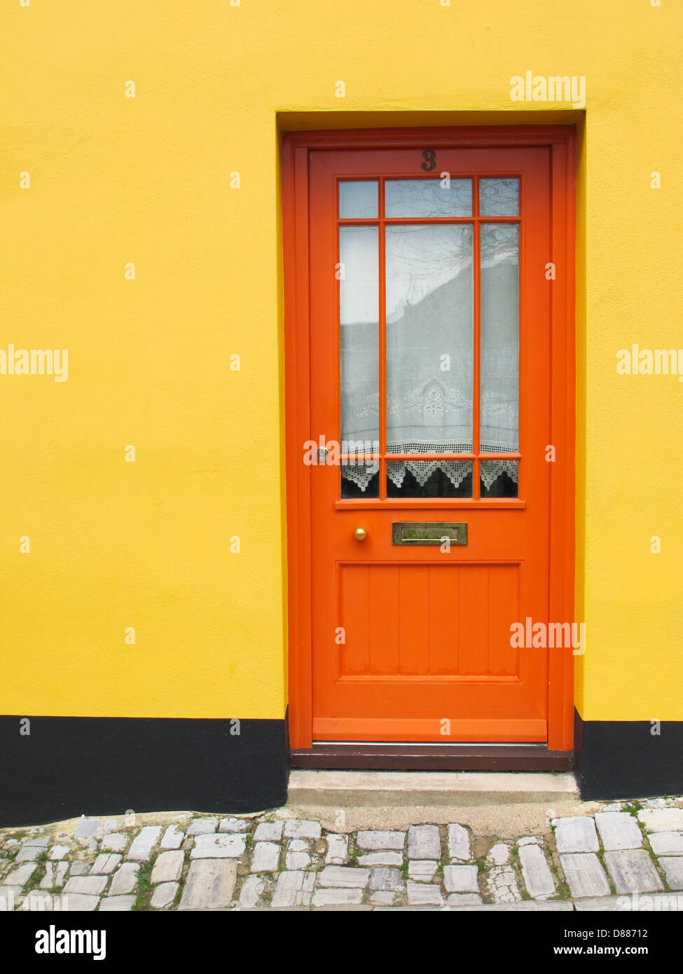 An orange door with a yellow wall Stock Photo