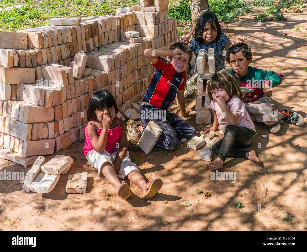 Five Hispanic children play with bricks near a Habitat for Humanity site in Luque, Paraguay. Stock Photo