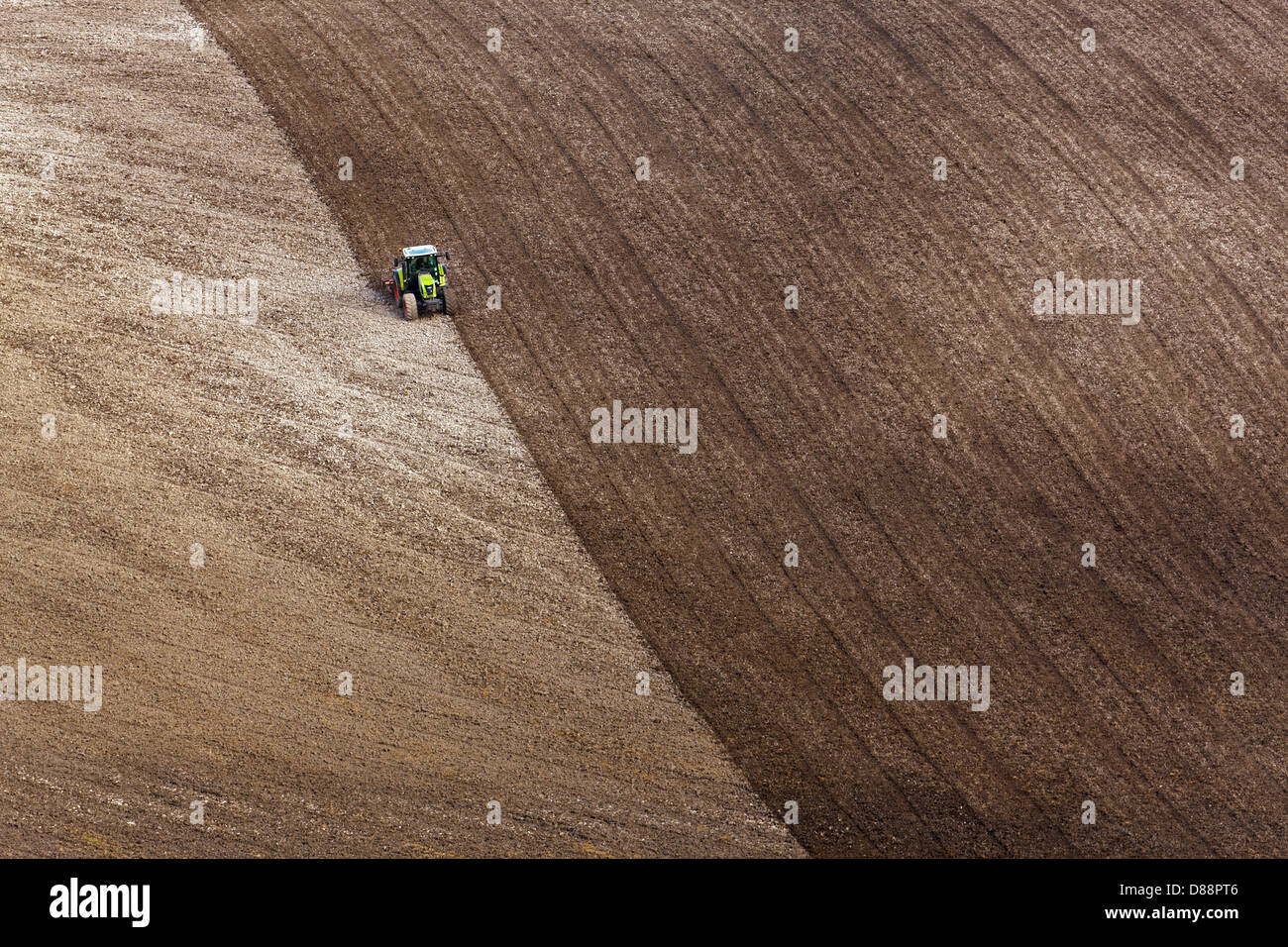 A lone tractor ploughing a field on the South Downs in Hampshire UK, Stock Photo