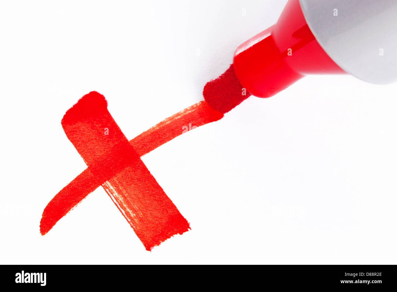 Close-up photo of a big red felt tip marker pen writing a cross X on white paper Stock Photo
