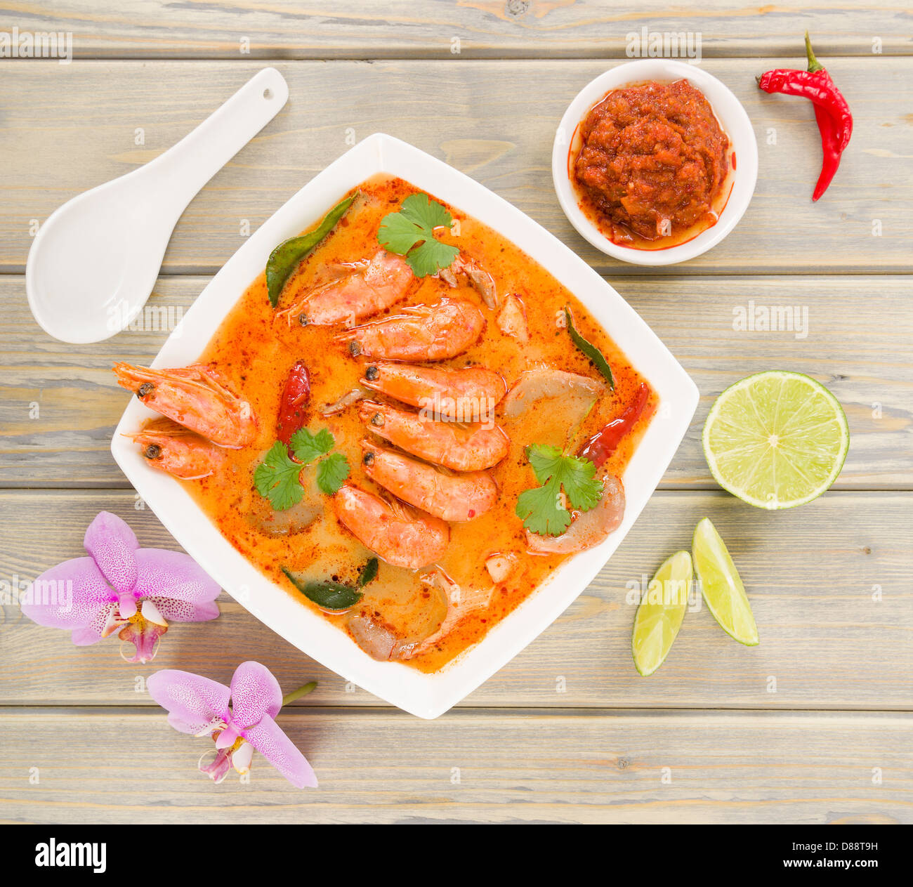 Tom Yum Nam Khon - Creamy Thai soup with prawns and mushrooms garnished with coriander and served with lime wedges. Stock Photo
