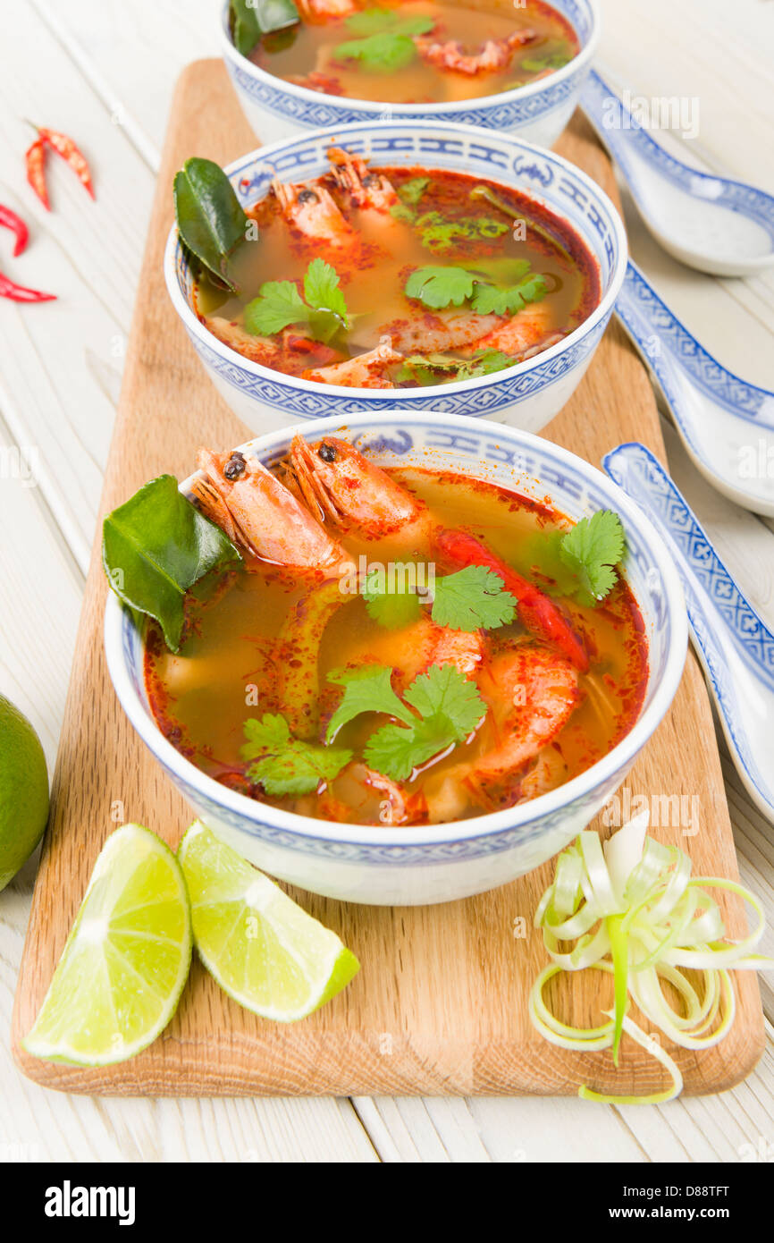 Tom Yum Goong - Thai clear hot and sour soup with king prawns and oyster mushrooms served with lime wedges. Stock Photo