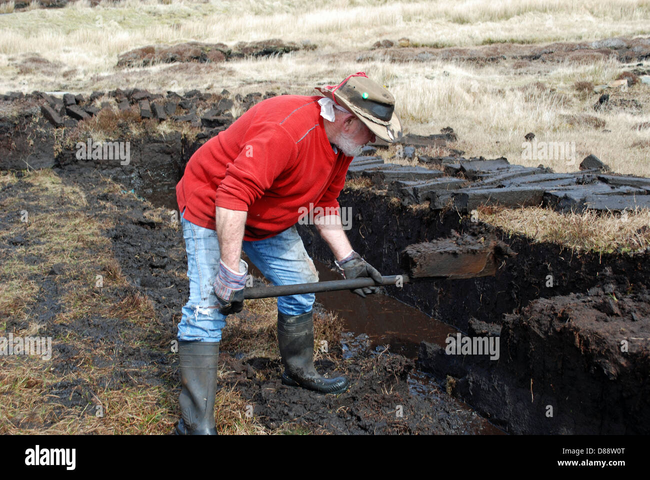 Man cutting turf in a peat bog on Aranmore island, in County Donegal. Stock Photo